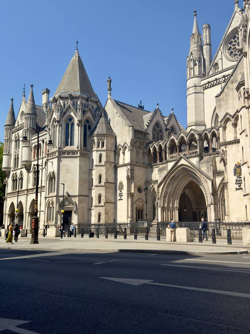 The Gothic stone frontage of the Royal Courts of Justice on the Strand, London, under a blue sky